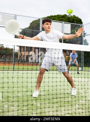 Giovane ragazzo concentrato che gioca a paddle tennis all'aperto Foto Stock