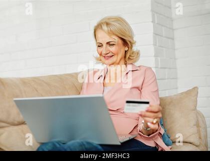 senior felice donna anziana laptop online shopping carta di credito e-commerce ordine di acquisto wireless fatture commercio Foto Stock