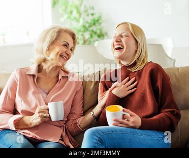 Coppia in pensione che partecipa alla videochiamata online su gadget remoto  con bambini che vivono lontano dai genitori. Donna elegante che indossa le  cuffie wireless mentre l'uomo dal bearato grigio guarda teneramente