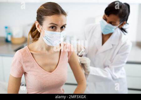 Fidato medico femmina che fa l'iniezione alla donna Foto Stock
