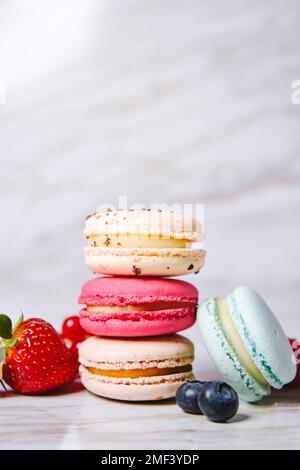 Rosa Macaron, arancione e beige, blu su marmo. Un bellissimo dessert francese. Frutta, fragole e mirtilli, mirtilli, r Foto Stock