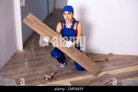 Riparatore femmina che installa pavimenti in laminato nell'appartamento Foto Stock