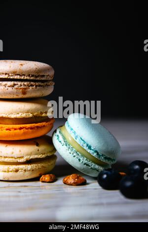 Torte di macaron colorate. Piccoli dolci francesi. Amaretti francesi dolci e colorati. Molti macaron gustosi con lamponi di bacche fresche e mirtilli, Foto Stock