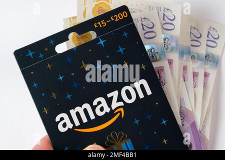 Immagine ravvicinata della carta regalo Amazon e blocco di denaro in una mano. Stafford, Regno Unito, 24 gennaio 2023 Foto Stock