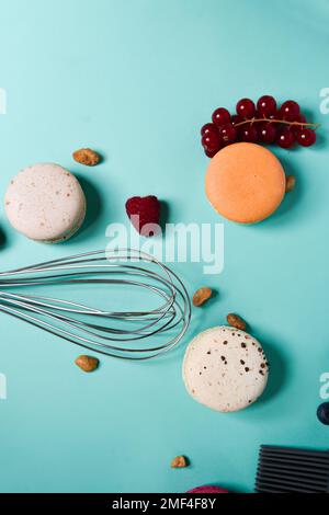Macaron colorati. Piccoli dolci francesi. Cottura, frusta, macaron spezzati, frutta, fragole, lamponi e more. Processo di cottura su un blu Foto Stock