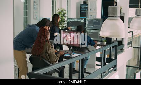 Diversi gruppi di sviluppatori di app che lavorano con computer hacked, che si occupano della sicurezza degli errori di sistema e dell'avviso di hacking. Gli amministratori IT leggono il messaggio di distorsione degli errori del computer per risolvere gli attacchi informatici. Foto Stock