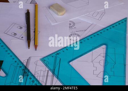 Immagine di una tabella di un ingegnere con piani disegnati con cad con righello, impostare quadrati e matite da disegno sullo sfondo. Foto Stock