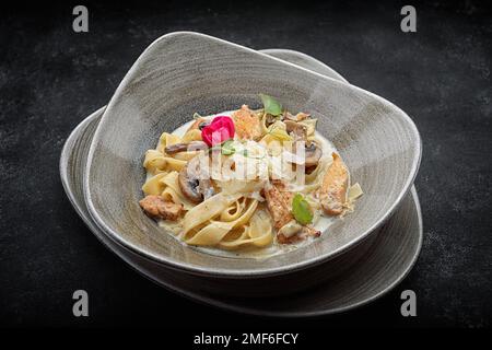 Pasta con pollo, funghi, salsa e formaggio, su un piatto Foto Stock