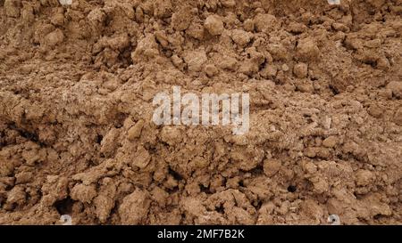 Primo piano di macro vista di sporco rosso o fango di suolo di palo da terra agricola. Sfondo del suolo con spazio di testo. Struttura full frame motivo naturale Foto Stock