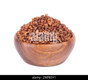 Tè di grano saraceno in ciotola di legno, isolato su sfondo bianco. Grani di grano saraceno interi arrostiti. Fagopyrum tataricum Foto Stock