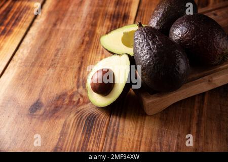 Metà avocado messicano (persea americana) su rustico tavolo di legno. Ingrediente principale per preparare guacamole. Copiare lo spazio per il testo. Foto Stock