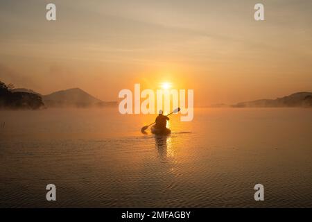 Donne in kayak file nel serbatoio durante l'alba, Harirak parco forestale Huai Nam Man Reservoir Loei Thailandia 21 gennaio 2023 Foto Stock