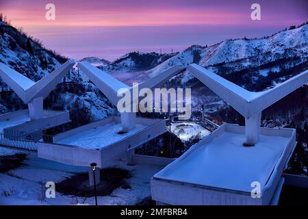 Il paesaggio della luminosa pista di pattinaggio Medeu da caffè inghiottire la vecchia architettura URSS in Tian Shan montagne al tramonto rosa nella città di Almaty, Kazakistan Foto Stock