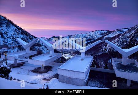 Il paesaggio della luminosa pista di pattinaggio Medeu da caffè inghiottire la vecchia architettura URSS in Tian Shan montagne al tramonto rosa nella città di Almaty, Kazakistan Foto Stock