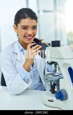 Potrei passare a qualcosa di straordinario. Ritratto di un giovane scienziato utilizzando un microscopio in laboratorio. Foto Stock