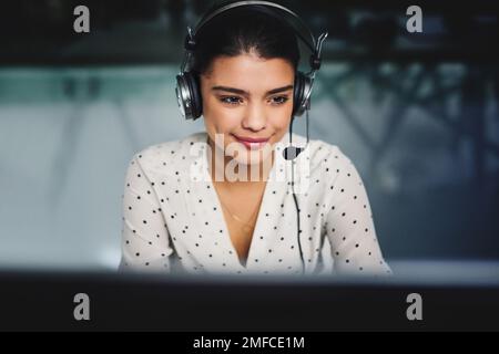 Shes sempre su chiamata. una giovane e attraente donna d'affari che lavora tardi in un call center. Foto Stock