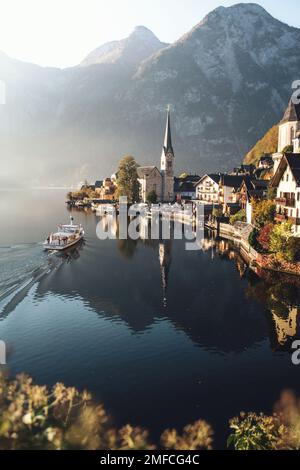 Vista panoramica da cartolina del famoso villaggio montano di Hallstatt nelle Alpi austriache con una nave passeggeri alla bellissima luce mattutina all'alba. Foto Stock