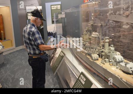 Virgil Greene, che ha servito a bordo della USS Newport News (CA 148) come tecnico della caldaia di seconda Classe, fornisce alcune informazioni riguardo al suo servizio durante una visita al Museo Navale di Hampton Roads. Greene ha servito a bordo di Newport News dal 1969-1973 durante la guerra del Vietnam, ed è raffigurato con un grande modello dell'incrociatore. Il grande modello di nave è in mostra al museo come parte della loro mostra “la guerra dei Temila giorni in mare: Gli Stati Uniti Navy in Vietnam, 1950-1975.” Il museo si trova al secondo piano dell'edificio Nauticus nel centro di Norfolk, Virginia. Foto Stock