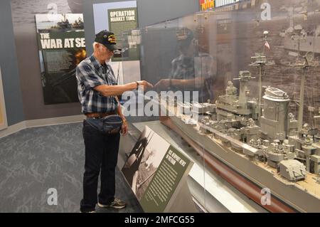 Virgil Greene, che ha servito a bordo della USS Newport News (CA 148) come tecnico della caldaia di seconda Classe, fornisce alcune informazioni riguardo al suo servizio durante una visita al Museo Navale di Hampton Roads. Greene ha servito a bordo di Newport News dal 1969-1973 durante la guerra del Vietnam, ed è raffigurato con un grande modello dell'incrociatore. Il grande modello di nave è in mostra al museo come parte della loro mostra “la guerra dei Temila giorni in mare: Gli Stati Uniti Navy in Vietnam, 1950-1975.” Il museo si trova al secondo piano dell'edificio Nauticus nel centro di Norfolk, Virginia. Foto Stock