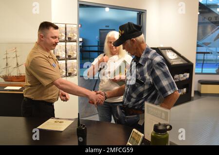 Il volontario attivo LS2(SW) Charles Fowler, assegnato alla USS Gerald R. Ford (CVN 78), presenta una spilla e una moneta commemorativa a Virgil Greene, che ha servito a bordo della USS Newport News (CA 148) come tecnico della caldaia di seconda Classe dal 1969-1973 durante la guerra del Vietnam. Greene stava visitando la mostra del Museo Navale di Hampton Roads, “la guerra dei dieci Mille giorni in mare: Gli Stati Uniti Navy in Vietnam, 1950-1975.” Il museo si trova al secondo piano dell'edificio Nauticus nel centro di Norfolk, Virginia Foto Stock