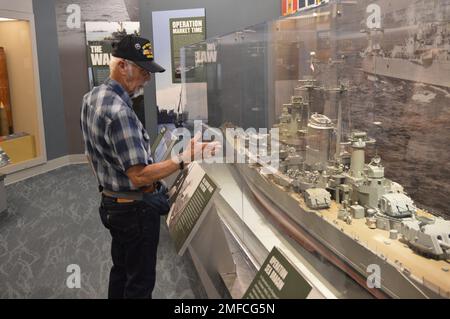 Virgil Greene, che ha servito a bordo della USS Newport News (CA 148) come tecnico della caldaia di seconda Classe, fornisce alcune informazioni riguardo al suo servizio durante una visita al Museo Navale di Hampton Roads. Greene ha servito a bordo di Newport News dal 1969-1973 durante la guerra del Vietnam, ed è raffigurato con un grande modello dell'incrociatore. Il grande modello di nave è in mostra al museo come parte della loro mostra “la guerra dei Temila giorni in mare: Gli Stati Uniti Navy in Vietnam, 1950-1975.” Il museo si trova al secondo piano dell'edificio Nauticus nel centro di Norfolk, Virginia. Foto Stock