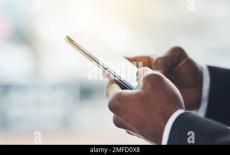 Raggiungendo fuori alla sua lista vasta delle reti. Primo piano di un uomo d'affari irriconoscibile utilizzando un cellulare in un ufficio. Foto Stock