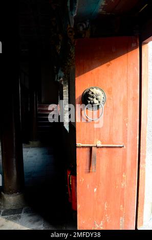 Immagine verticale a colori del leone in stile cinese sulla porta di legno rosso. - fotografia di stock Foto Stock