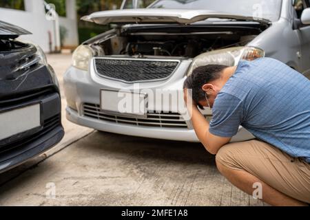 L'uomo si è rovesciato e si siede l'automobilista in Crash per la frode di assicurazione di arresto che esce dall'automobile Foto Stock