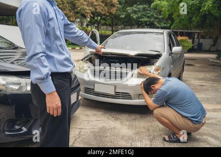 L'uomo si è rovesciato e si siede l'automobilista in Crash per la frode di assicurazione di arresto che esce dall'automobile Foto Stock