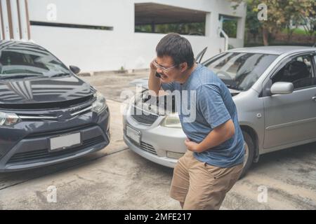 L'uomo si è rovesciato e si siede l'automobilista in Crash per la frode di assicurazione di arresto che esce dall'automobile Foto Stock