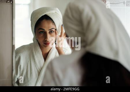 Giovane donna in accappatoio guardando il bagno miror dopo aver fatto la doccia Foto Stock