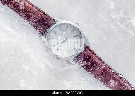 Orologio analogico congelato sotto il ghiaccio con cinturino in pelle marrone. Concetto di blocco nel tempo Foto Stock