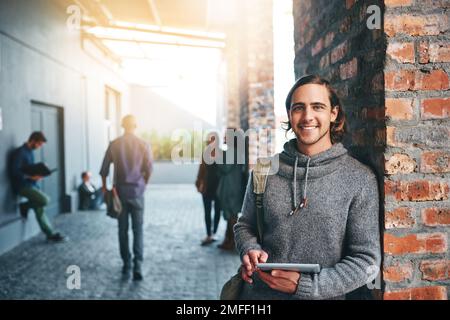 Iniziare un nuovo capitolo nella mia vita. un giovane uomo che utilizza un tablet digitale all'aperto nel campus. Foto Stock