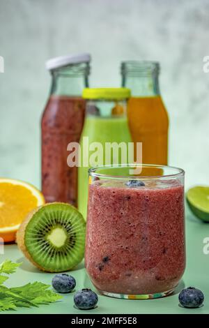 Frullati verdi, arancioni, rossi in bottiglie di vetro e frullati di vetro. Foto Stock