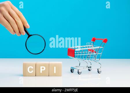 CPI - Consumer Price Index Symbol.Letter Block in word CPI abbreviazione dell'indice dei prezzi al consumo con una lente d'ingrandimento in mano di donna vicino a sho vuoto Foto Stock