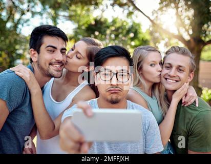 Selfie designato. un giovane gruppo di amici che scattano selfie mentre sorseggiano qualche drink al sole estivo. Foto Stock