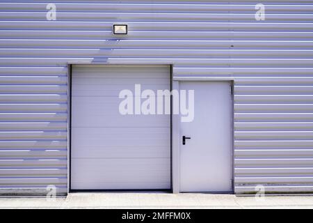 persiane avvolgibili sull'ingresso della porta di uscita antincendio dell'edificio grigio nell'unità industriale commerciale Foto Stock