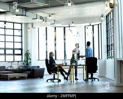 Youre facendo il lavoro grande. Scatto completo di due uomini d'affari che scuotono le mani mentre lavorano nel loro ufficio. Foto Stock