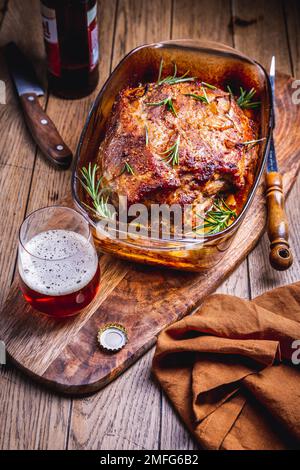 Carne di maiale arrosto con patate, rosmarino e salsa di birra in casseruola Foto Stock