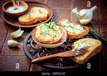 Pane all'aglio fatto in casa o fette di baguette con burro all'aglio ed erbe aromatiche sul tavolo da cucina Foto Stock
