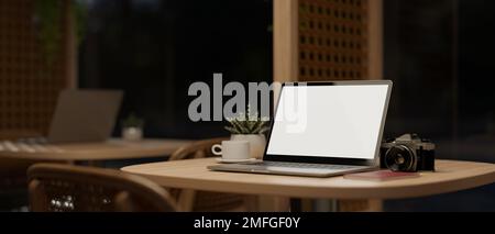 Portatile portatile schermo bianco mockup, macchina fotografica, caffè tazza e arredamento pianta sul tavolo in bella e minimal bar di notte. luogo di lavoro, lavoro Foto Stock