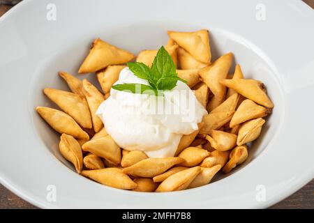 Ravioli turchi fritti e croccanti su un piatto di porcellana bianca Foto Stock