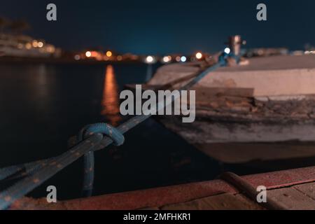 Esposizione prolungata di una barca nella laguna di El Gouna con vista notturna della città illuminata Foto Stock