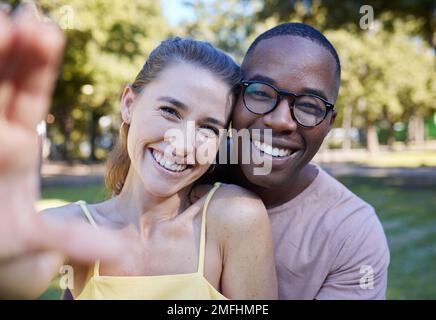 Amore, sorriso e selfie con coppia interrazziale al parco per il relax, social media e la pace sulla data romantica. Supporto, tempo felice e di qualità con il nero Foto Stock