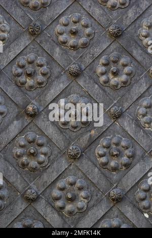 Una vecchia porta in metallo, cancelli forgiati, rivetti sulla facciata di una porta in ghisa, una maniglia rotonda per aprire la porta, la texture di vecchio ferro. Phot di alta qualità Foto Stock