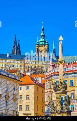 Guglie di St. La Cattedrale di Vito, il Castello di Praga e gli edifici sulla collina attraverso la colonna della Santissima Trinità su Malostranske Namesti, in Cechia Foto Stock