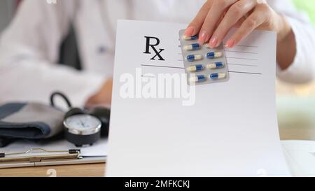 Medico seduto al tavolo con gli strumenti per la diagnostica medica e mostra prescrizione e pacchetto di farmaci. Foto Stock