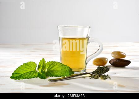 Tè alle erbe al limone in una tazza di vetro con balsamo al limone Foto Stock