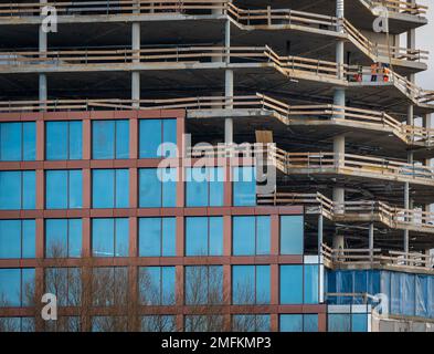 Alto e moderno edificio in costruzione, facciata e finestre parzialmente rifinite Foto Stock