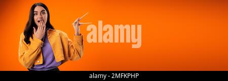 Giovane donna eccitato che tiene bacchette di bambù isolato su arancione, banner, immagine stock Foto Stock